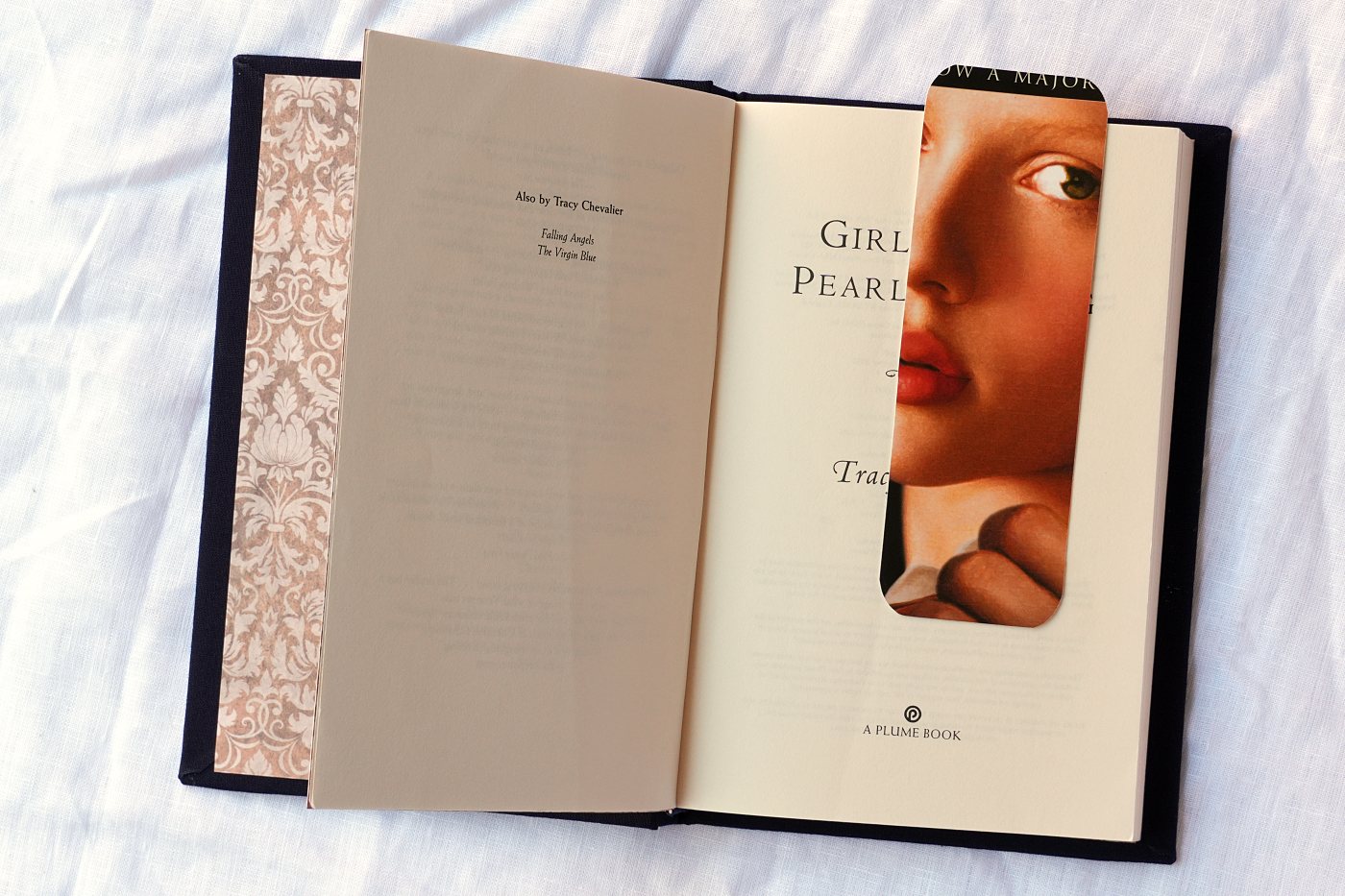 The book open, showing damask endpapers and a bookmark cut from the original paperback cover
