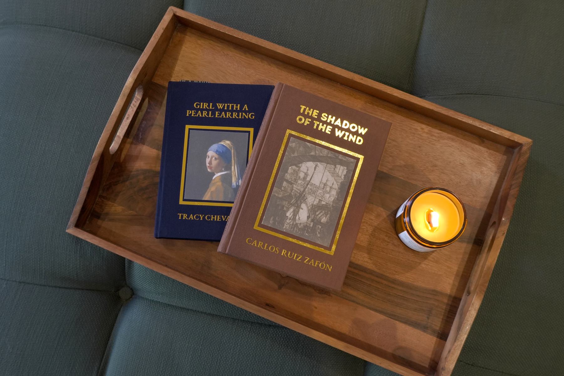 Two rebound books on a wooden tray beside a lit candle